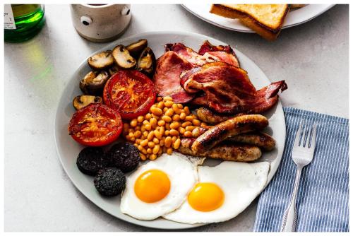 um prato de comida para o pequeno-almoço com ovos, bacon, feijão e tomate em Chandos Premier Folkestone (Channel Tunnel) Hotel em Folkestone