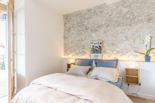 um quarto com uma cama e uma parede de pedra em Jondoni Laurendi Kanbo em Cambo-les-Bains