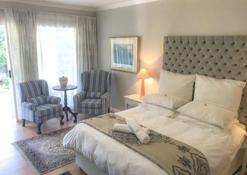 1 Schlafzimmer mit einem großen Bett und 2 Stühlen in der Unterkunft Lavender Suite in Kapstadt
