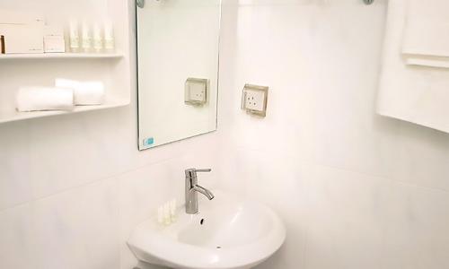 a white bathroom with a sink and a mirror at Amina Residency in Male City