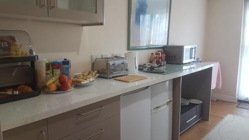 a kitchen with a counter with a microwave and fruit on it at Arman Lodge House in Peterborough