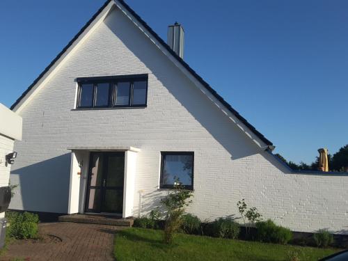 una casa bianca con finestre nere e un vialetto di Haus Ostseestrand36 a Timmendorfer Strand