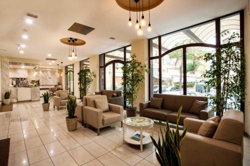un hall avec des canapés, des tables et des plantes dans l'établissement Hotel King, à Rimini