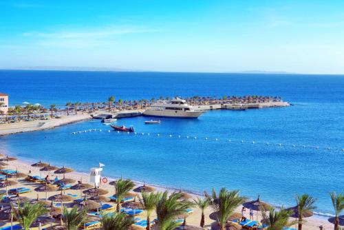 Pickalbatros Aqua Blu & Vista Resort - Hurghada في الغردقة: مجموعة من الناس على شاطئ مع سفينة سياحية
