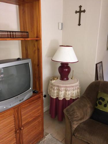 uma sala de estar com uma televisão e um candeeiro sobre uma mesa em Air on Edward em Pretoria