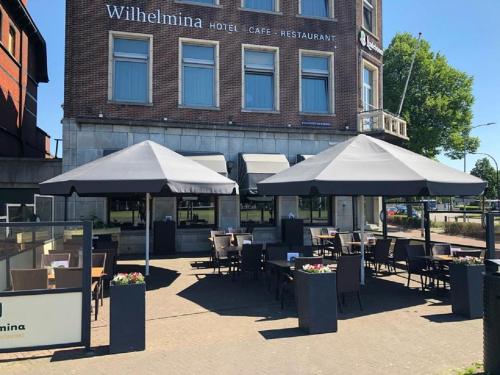 a patio with tables and umbrellas in front of a building at Hotel Wilhelmina in Venlo