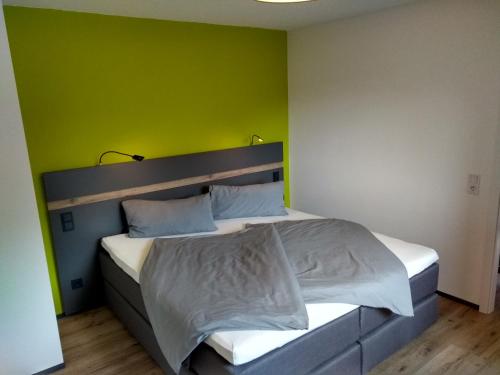 1 dormitorio con 1 cama con pared verde en Apartment Haus Sembachtal en Winterstein