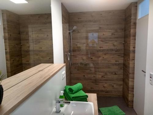 a bathroom with a sink and a shower with wooden walls at Apartment Haus Sembachtal in Winterstein