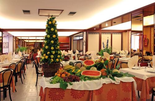 une salle à manger avec un arbre de Noël sur les tables dans l'établissement Hotel Gaggiano, à San Giovanni Rotondo