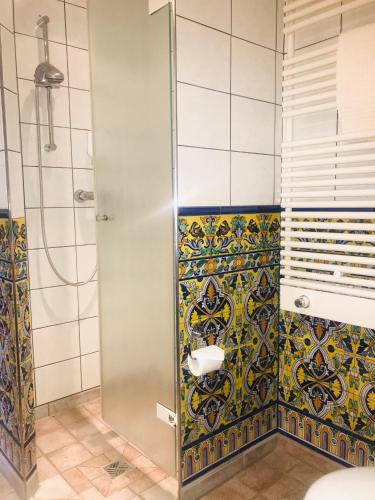 a bathroom with a shower and a tile wall at Hotel Spanischer Hof in Gröditz