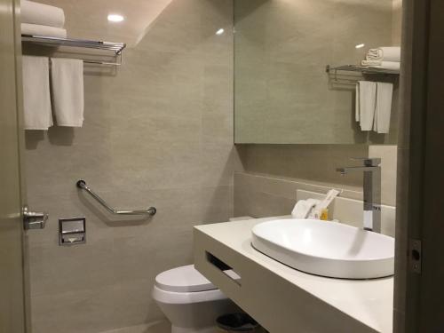 a bathroom with a sink and a toilet and a mirror at L'Fisher Hotel Bacolod in Bacolod
