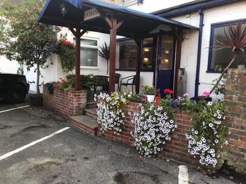a house with a brick wall with flowers in front of it at Penny Farthing Hotel & Cottages in Lyndhurst