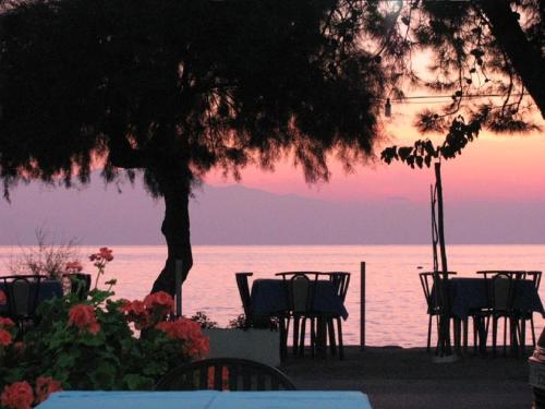 ネア・カリクラティアにあるFerienhaus "Arizones", Nea Kallikratia, Chalkidikiのテーブルと椅子が備わる水上の夕日