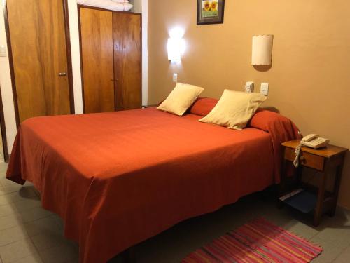 1 dormitorio con 1 cama con sábanas de color naranja y teléfono en Termas Del Sol en Termas de Río Hondo