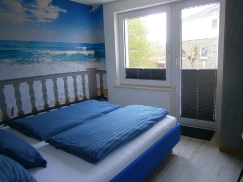 a bedroom with a bed with a window and blue walls at Haus Steinbach in Kellenhusen