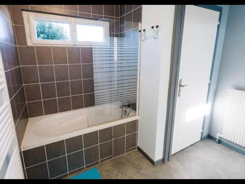 La salle de bains est pourvue d'une baignoire et d'une fenêtre. dans l'établissement charmante maison lumineuse et confortable, à Le Poinçonnet