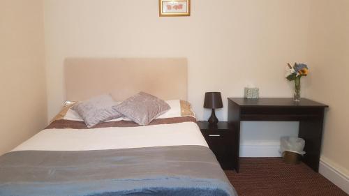 a bedroom with a bed and a table with a vase of flowers at Arman Lodge House in Peterborough