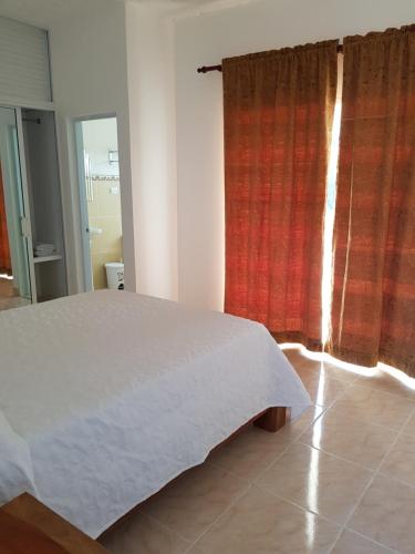 a bedroom with a white bed and a red curtain at Apartamentos Nuevo Amanecer in Río San Juan