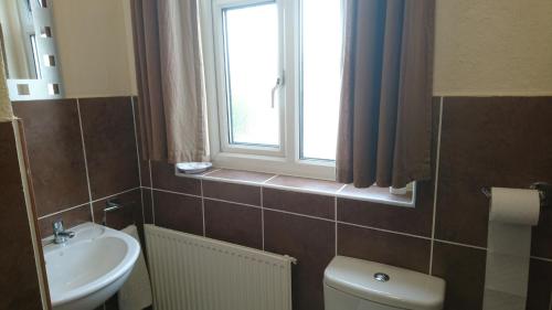 a bathroom with a toilet and a sink and a window at Arman Lodge House in Peterborough
