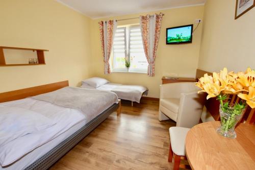 a bedroom with two beds and a table with flowers at Willa Helios in Darlowko
