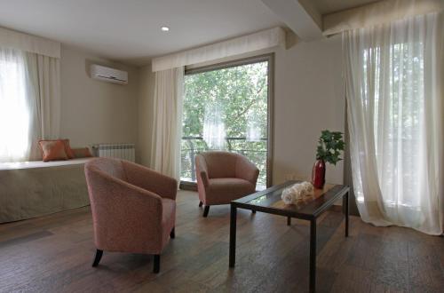 a living room with two chairs and a table and a window at Plaza Paradiso Petit Hotel in Chacras de Coria
