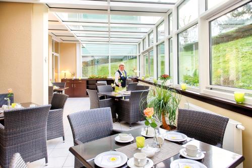 a person standing in a restaurant with tables and chairs at Hotel Carolinenhof in Berlin