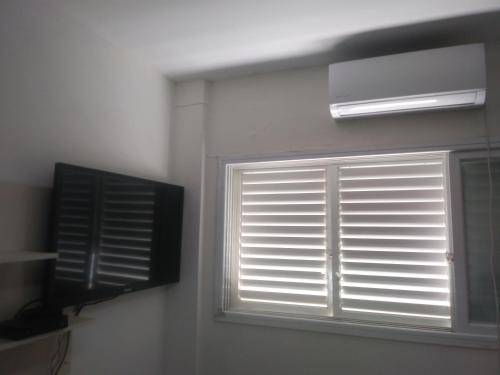 a window with blinds and a television in a room at Namaste in Tel Aviv