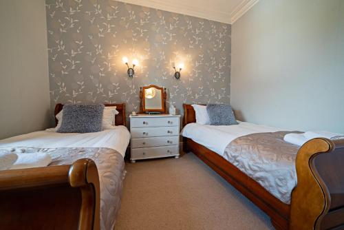 a bedroom with two beds and a mirror on the wall at The Rowan Tree Country Hotel in Aviemore