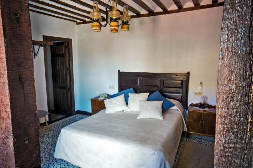 a bedroom with a large bed with blue pillows at Casa del Hortelano in Chinchón