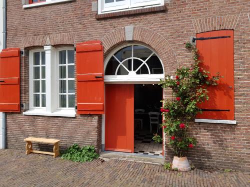 eine offene Tür zu einem Backsteingebäude mit roten Türen in der Unterkunft Het Pakhuis Schiedam in Schiedam