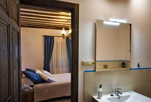 a bathroom with a sink and a mirror and a bed at Casa del Hortelano in Chinchón