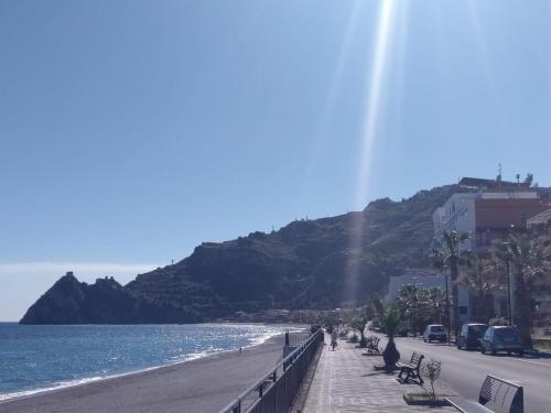 a beach with a bridge and the ocean and a mountain at SANT'ALESSIO BEACH HOLIDAY in SantʼAlessio Siculo