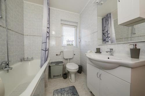 een witte badkamer met een wastafel, een toilet en een bad bij Central Apartment Castle Cippico in Kaštela