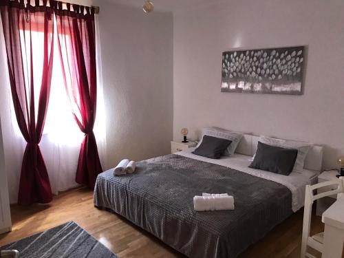 1 dormitorio con 1 cama con cortinas rojas y ventana en Studio Apartment Sabljic, en Kaštela