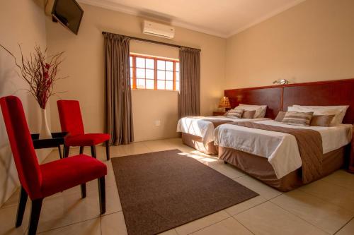 una camera con due letti e una sedia rossa di Tambati Overnight and Conference Center a Polokwane