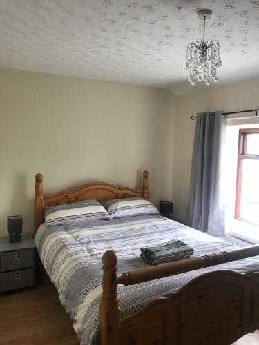 a bedroom with a large wooden bed with a chandelier at Third Tree House in Coleraine