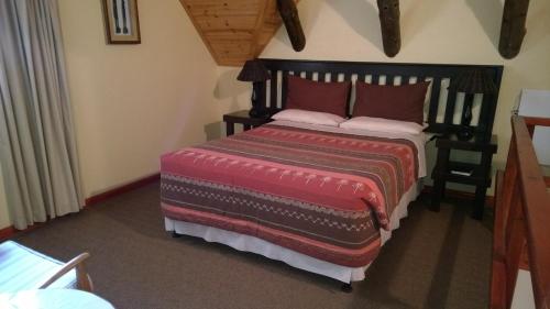 a bedroom with a large bed with a red blanket at Baviana Beach Lodge in Jacobs Bay