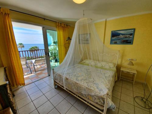 a bedroom with a bed with a canopy and a balcony at Rocas del mar - Casa Remo in Costa Del Silencio