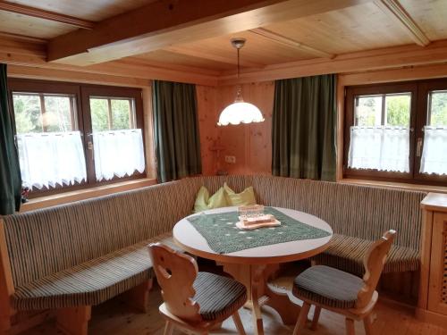 a dining room with a table and chairs and windows at Holzfällerhaus Melkstatt in Auffach