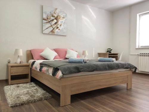 ein Schlafzimmer mit einem großen Holzbett mit rosa Kissen in der Unterkunft Apartman Danijela in Otočac