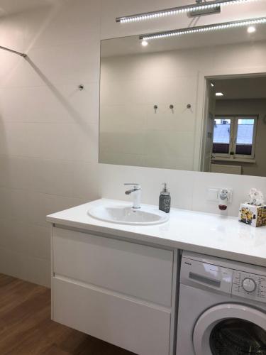 a bathroom with a sink and a washing machine at Klimatyzowany Apartament Londyn in Kielce