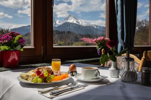 a table with a plate of food and a view of a mountain at Hotel Vier Jahreszeiten in Berchtesgaden