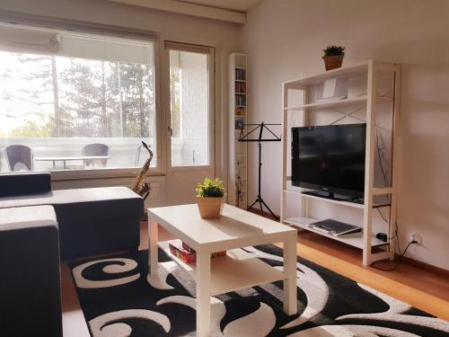 uma sala de estar com uma televisão e uma mesa em Home Away Holiday em Kuopio