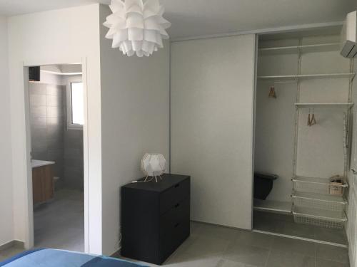 a bedroom with a black dresser and a chandelier at Charmant T2 Hauteurs de Bastia in Bastia