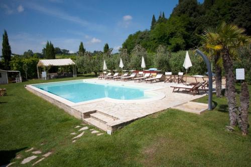 a swimming pool in a yard with chairs and umbrellas at Cevoli Country Resort in Lari
