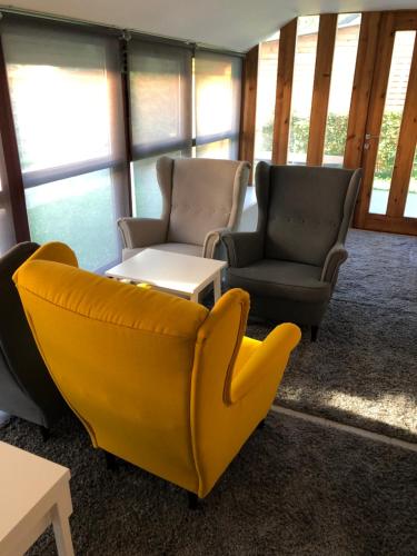 a living room with two chairs and a yellow couch at Hullám Apartman in Balatonlelle