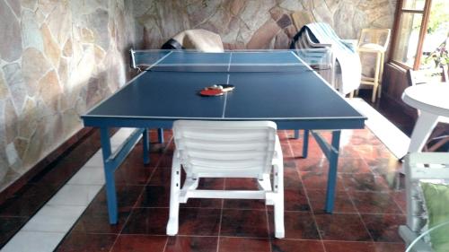 uma mesa de pingue-pongue azul com uma cadeira branca em Casa de Araras em Araras, Petrópolis