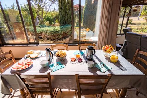 a table with food on it in a room with windows at Chambre d'hôtes Au Chant des Vents in Thurageau