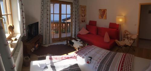a bedroom with a red bed and a red couch at ALPENFREUND in Mittenwald