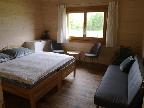 1 dormitorio con 1 cama, 2 sillas y ventana en Resort Radslavice, en Přerov